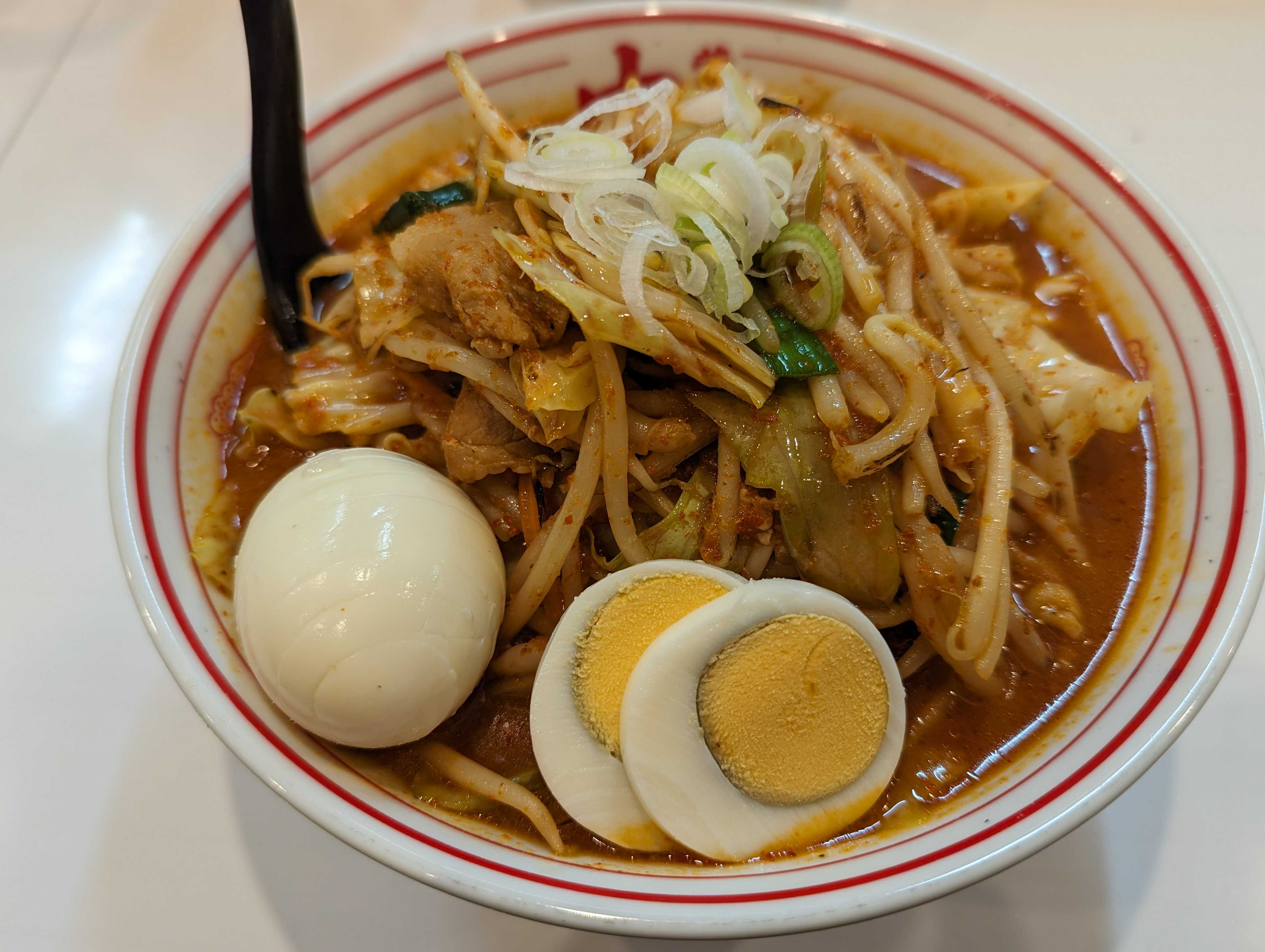 北極やさいシャキシャキにゆで卵がトッピングされている。左側に黒いレンゲが刺さっている。